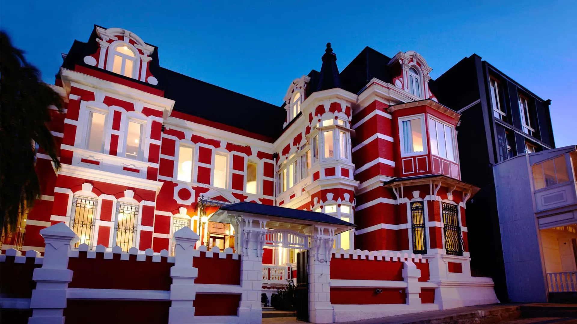 Fachada roja y blanca del Palacio Astoreca iluminada al atardecer