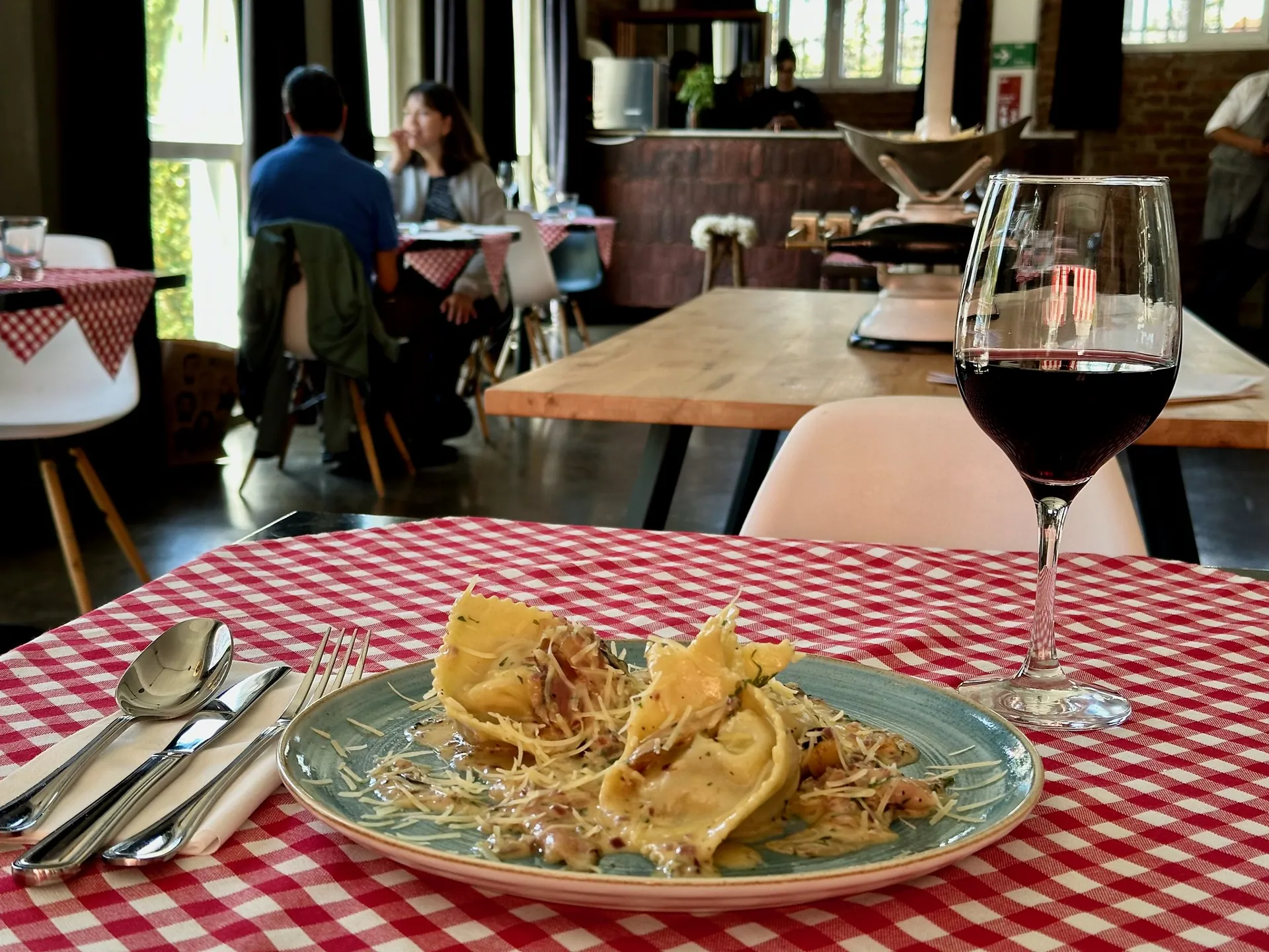 Tortelloni y vino sobre un mantel a cuadros en Pastalegre