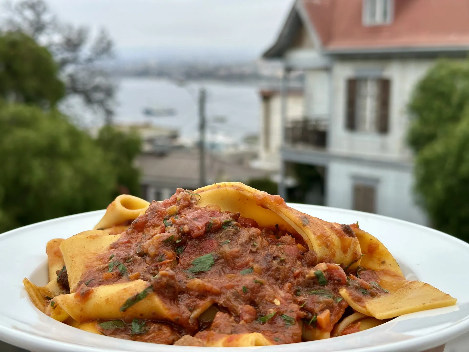 Pappardelle al ragú servido en la terraza de Pastalegre con vista a la bahía