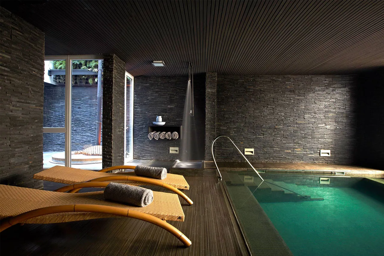 Piscina de Spa Alegre junto a las reposeras y paredes de pizarra